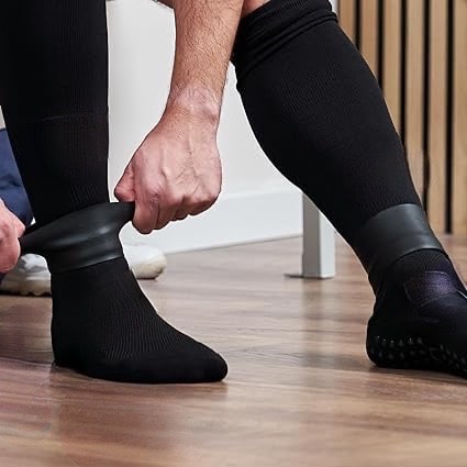 Person pulling Shinplex silicone bands over shin sleeves on hardwood floor
